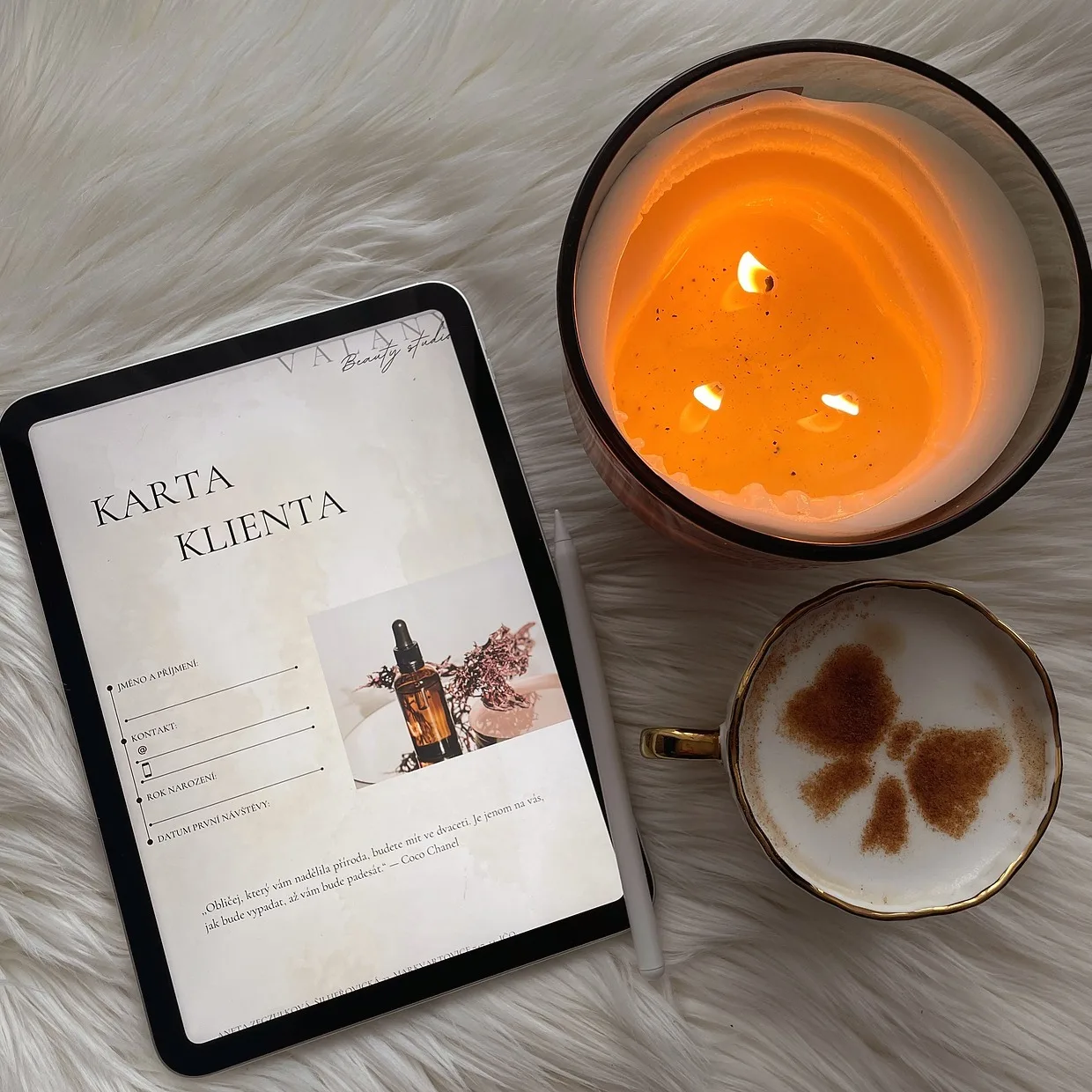 Karta klienta na iPadu, vedle ní zapálená svíčka a cappuccino